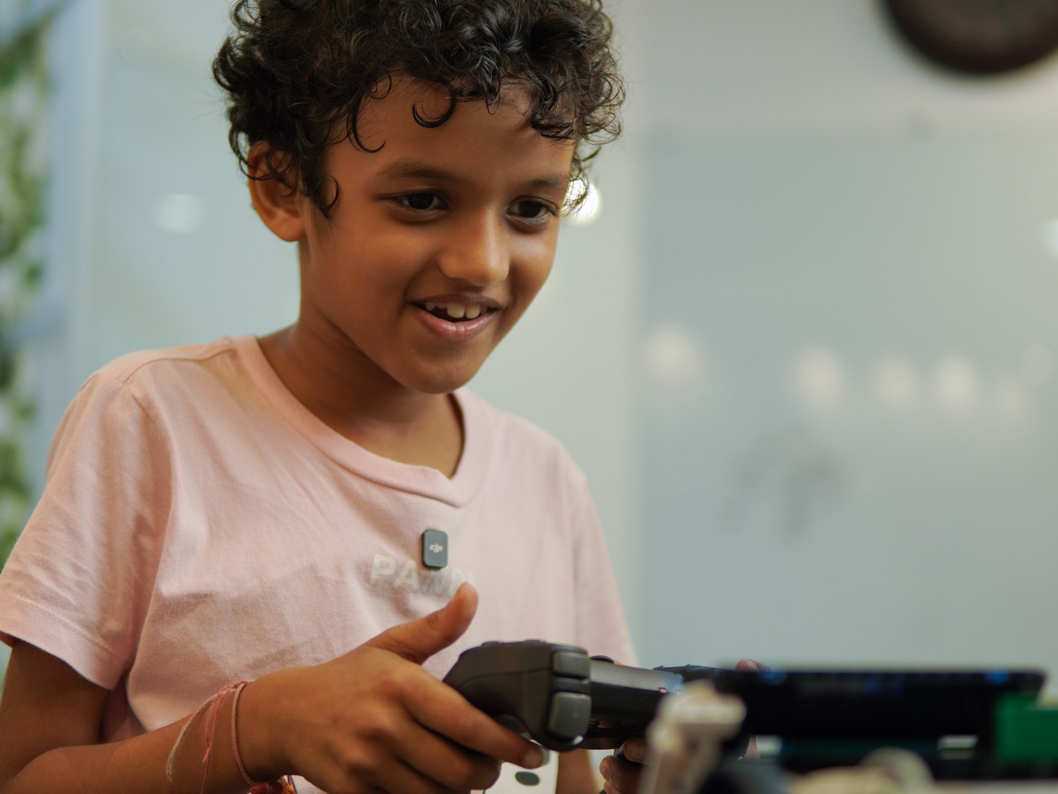 A Cubo Academy child smiling as he drives the robot he built