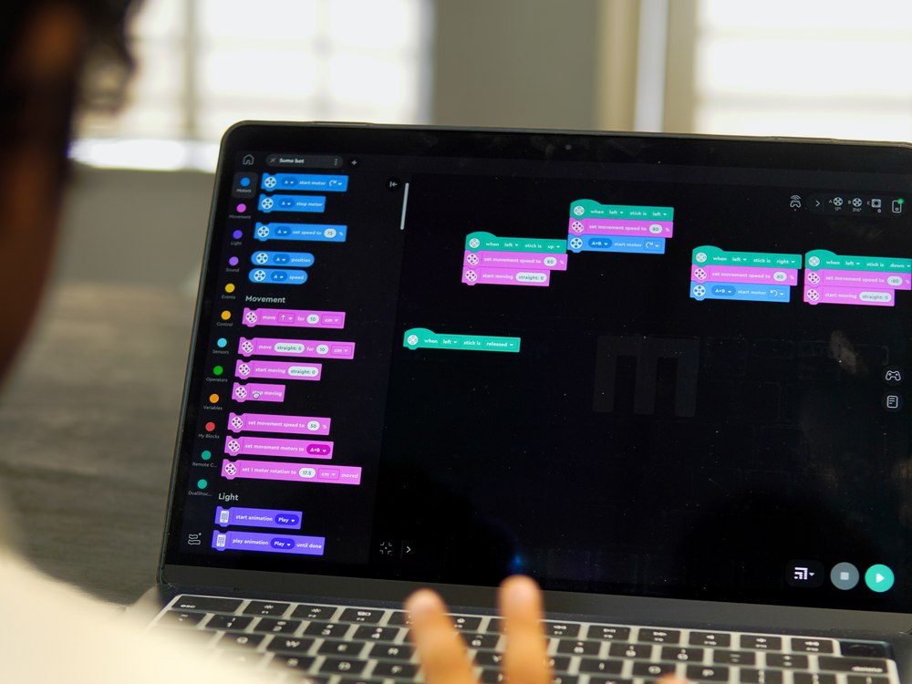 A Cubo Academy child at a laptop, planning their robot project in block code